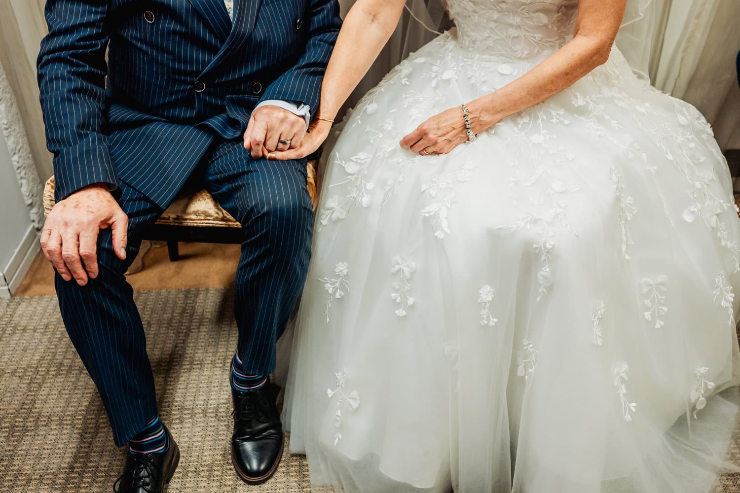 Older couple hold hands at their wedding, photo is off hands and feet