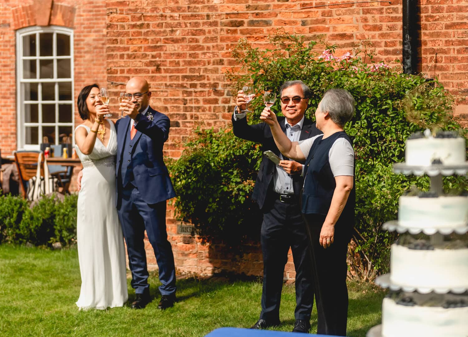 Couple cheers with champagne at their wedding with relatives. 2025 - A Weird and Wonderful Year of Weddings