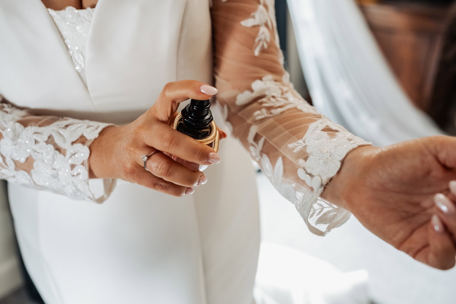 Bride sprays perfume on her wrist during wedding preparation