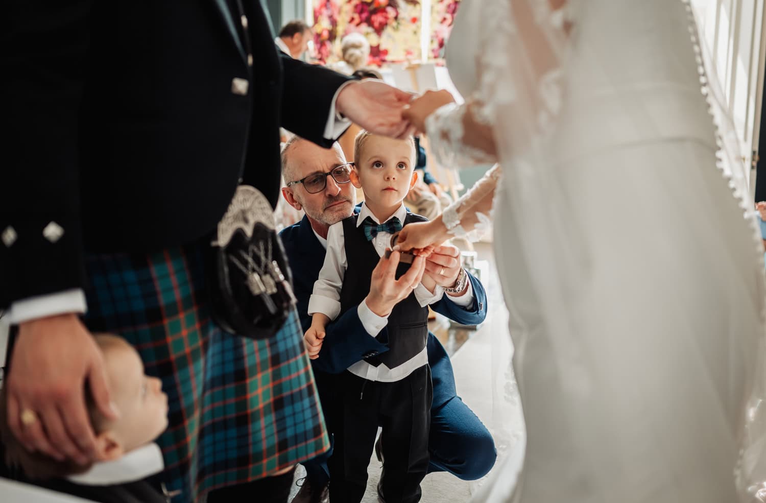 Couples son passes the ring to bride and groom during the wedding while being held by his grandfather