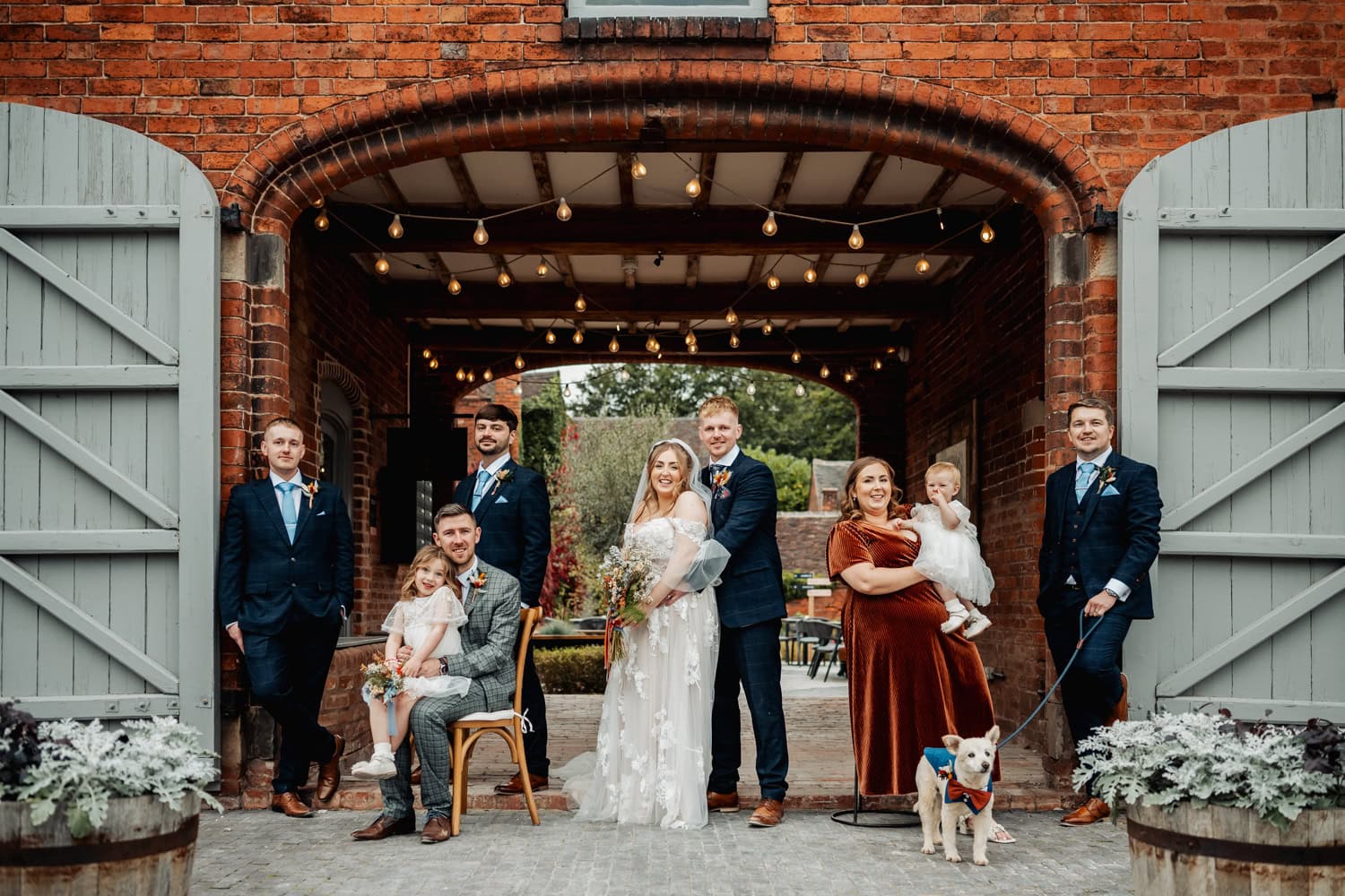 Bridal party at Blackbrook Barns, bridesmaid is rust orange dress, groomsman, suher holding dog
