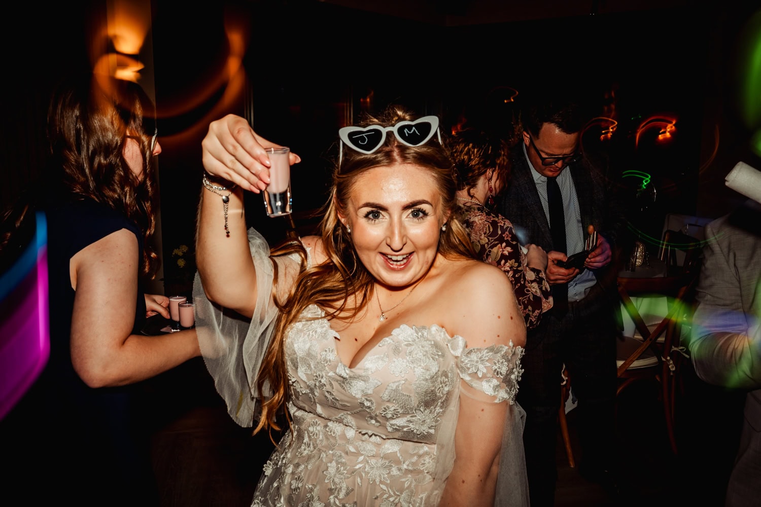 Bride drinks Wedding shots on dancefloor wearing heart shaped glasses